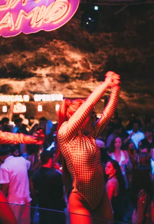 Bailarina em performance com braços erguidos no Imagine Punta Cana sob letreiro neon "AMOR" e luzes vermelhas