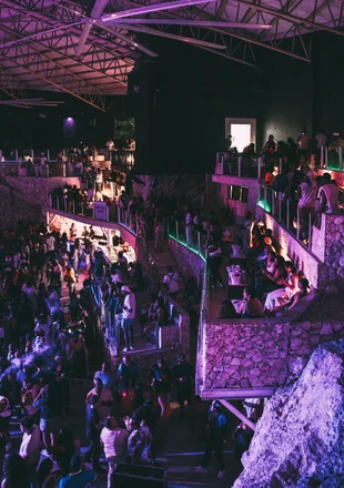 Ambiente do Imagine Punta Cana visto de cima: múltiplos níveis, público dançando e iluminação roxa na caverna natural