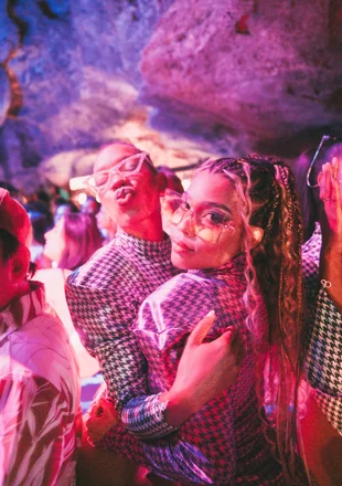 Casal curtindo a noite no Imagine Punta Cana, com máscara neon e iluminação rosa dentro da caverna