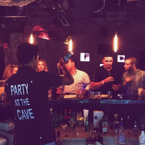 Bartender fazendo flair com garrafa de whisky atrás do bar da Imagine Punta Cana, discoteca dentro de caverna natural em Bávaro