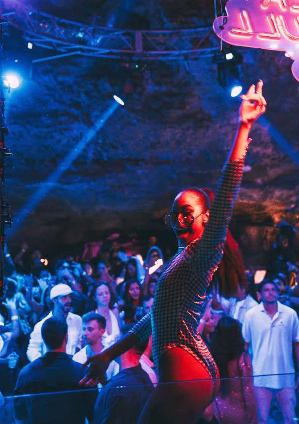 Bailarina em performance com luz vermelha no palco do Imagine Punta Cana, clube em caverna natural